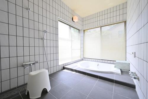 a white bathroom with a tub and a window at Izukogen 210 in Ito
