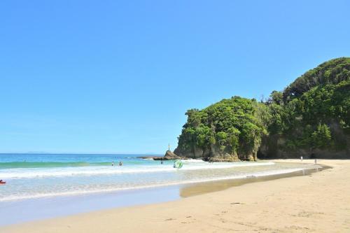 a beach with people swimming in the ocean at Izukogen 210 in Ito