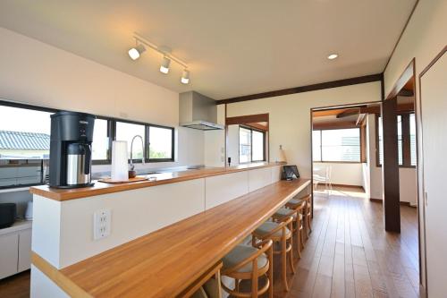 a kitchen with a long counter and some chairs at Izukogen 210 in Ito