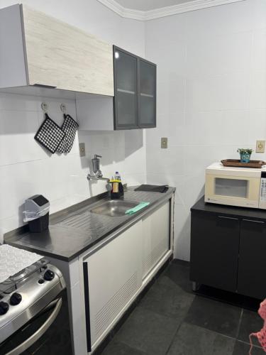a small kitchen with a sink and a microwave at Apartamento espaçoso com vista deslumbrante in São Vicente
