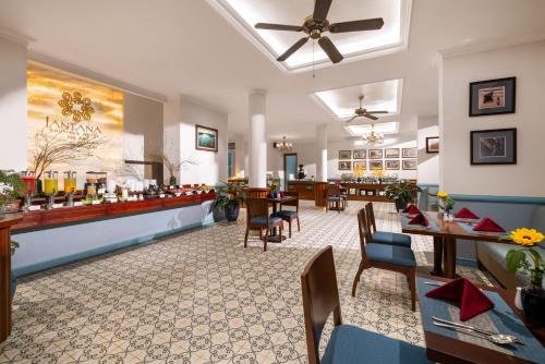 a restaurant with a bar with tables and chairs at Lantana Boutique Hoi An Hotel in Hoi An
