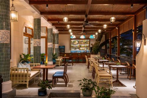 a restaurant with wooden ceilings and tables and chairs at Lantana Boutique Hoi An Hotel in Hoi An