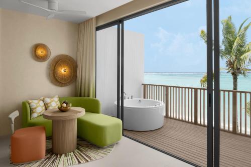 a bathroom with a green chair and a tub on a balcony at Centara Mirage Lagoon Maldives in Nakachchafushi