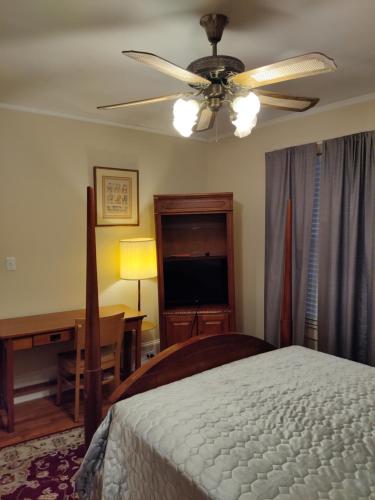 a bedroom with a bed with a ceiling fan and a desk at Brick House Retreat in Hamlet