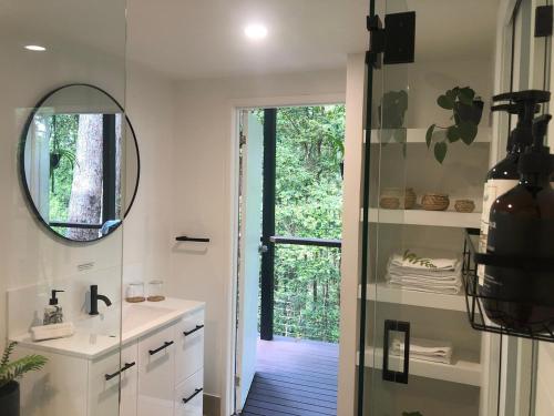 a bathroom with a sink and a mirror and a door at Earthly Retreat - Private Noosa Hinterland Getaway in Doonan