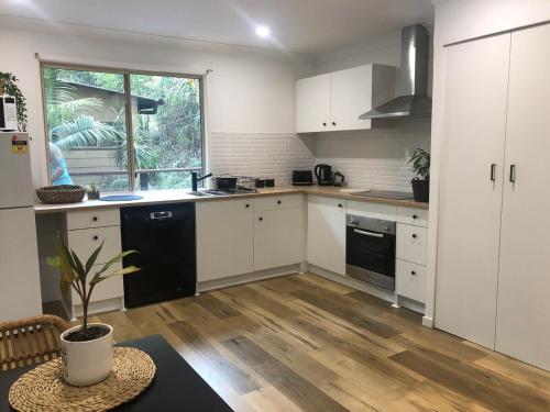 a kitchen with white cabinets and a black dishwasher at Earthly Retreat - Private Noosa Hinterland Getaway in Doonan