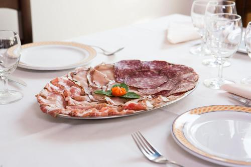 Een bord met vlees op een witte tafel met glazen. bij La Pioppa Agriturismo in Sacile