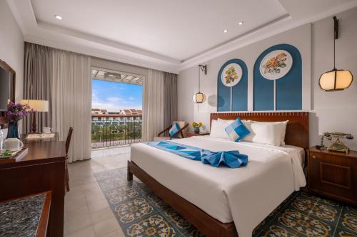 a bedroom with a large bed and a balcony at Lantana Boutique Hoi An Hotel in Hoi An