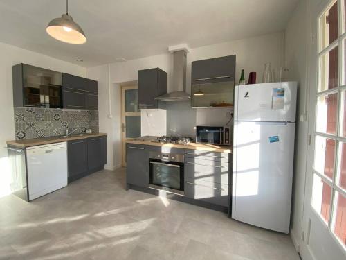 Il comprend une cuisine équipée d'un réfrigérateur blanc et d'une cuisinière. dans l'établissement Maison avec jardin à 450m de la mer à Trégastel - FR-1-368-453, à Trégastel