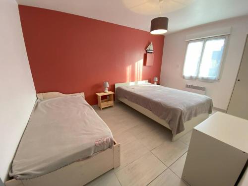 une chambre avec deux lits et un mur rouge dans l'établissement Maison avec jardin à 450m de la mer à Trégastel - FR-1-368-453, à Trégastel