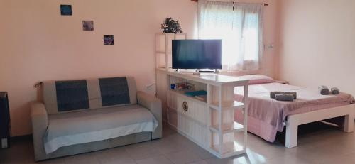 a small bedroom with a tv and a chair at Cabañas Alma del Sur in El Hoyo