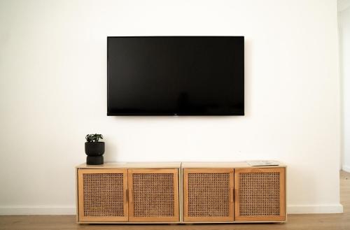 a television on a white wall with a wooden entertainment center at Villa Muraka Kalbarri in Kalbarri