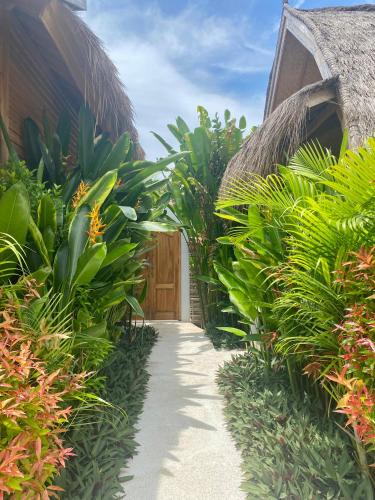 a garden path with plants and a wooden door at My Island Home Gili Air in Gili Air
