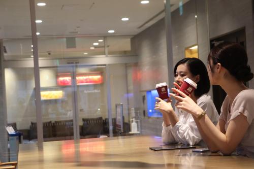 two women sitting at a table looking at their cell phones at Richmond Hotel Nagoya Shinkansen-guchi in Nagoya