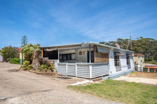a white house with a porch on a street at Durras Lake North Holiday Park in Durras