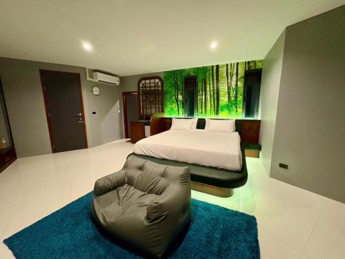 a bedroom with a bed and a chair and a couch at Chainam-Charmchuree residences cafe and spa in Ban Bang Bua Thong