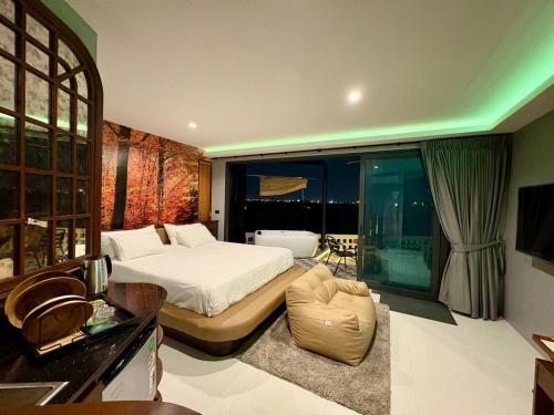 a bedroom with a bed and a large window at Chainam-Charmchuree residences cafe and spa in Ban Bang Bua Thong