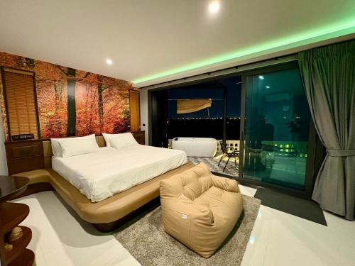 a bedroom with a bed and a chair and a window at Chainam-Charmchuree residences cafe and spa in Ban Bang Bua Thong