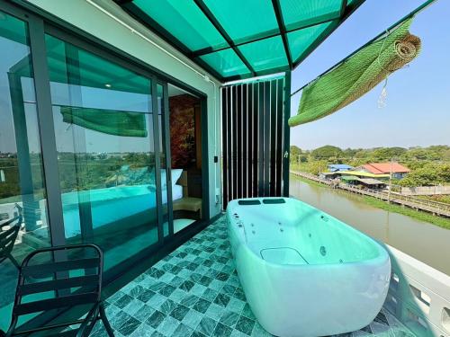 a bath tub on the balcony of a house at Chainam-Charmchuree residences cafe and spa in Ban Bang Bua Thong