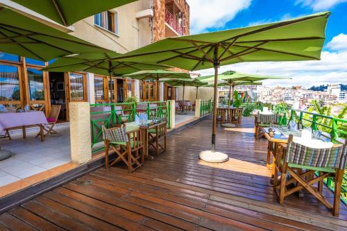 a patio with tables and chairs with green umbrellas at Palissandre ANTANANARIVO in Antananarivo
