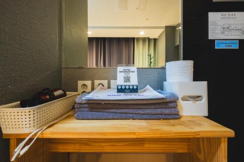 a pile of towels on a table in front of a mirror at MyeongDong New Stay Inn in Seoul
