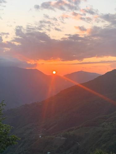 a sunset over a mountain range with the sun in the sky at Tianen Farm in Hualing