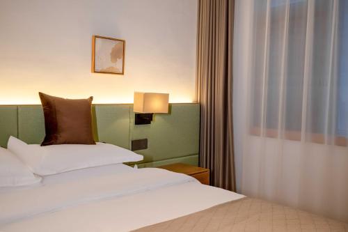 a bedroom with a bed with white sheets and brown pillows at Junlan Hotel 张家界郡澜民宿 in Zhangjiajie