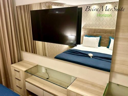 a mirror of a bedroom with a bed and a tv at Beira Mar Suite in Fortaleza