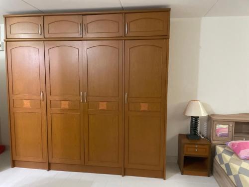 a bedroom with a large wooden cabinet next to a bed at Dailyroom by Anna T1-T12 in Nonthaburi