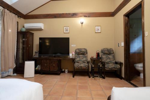 a living room with a flat screen tv and two chairs at クースクース in Fujikawaguchiko