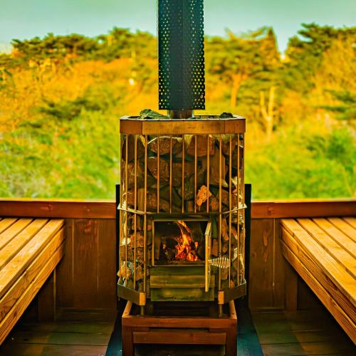 a woodburning stove with a fire in it on a porch at RENEST in Kobe