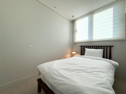 a bedroom with a white bed and a window at Eunhasu D&M Residence in Daejeon