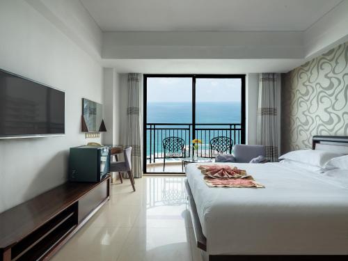 a bedroom with a bed and a television and a balcony at Barry Boutique Hotel Sanya in Sanya