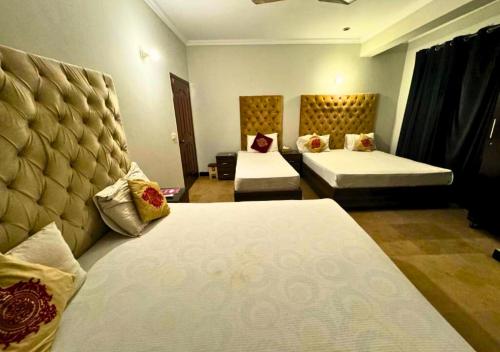 a hotel room with two beds and two at Doves Inn Hotel kalma Chowk in Lahore