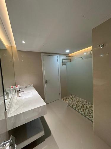 a bathroom with a shower and a sink and a mirror at East Coast Vacation Homes in Kalbā