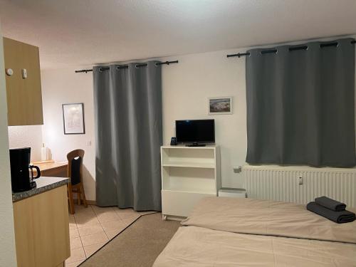 a bedroom with a bed and a desk with a television at Ferienapartment "An der Forellenschänke" in Sebnitz