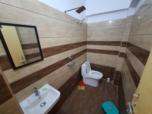 a bathroom with a sink and a toilet and a mirror at Ganpati Guest House in Ayodhya