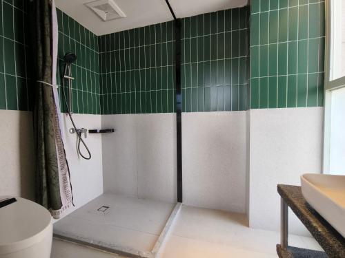 a shower in a bathroom with green and white tiles at West Street Hills Travel B&B in Quanzhou
