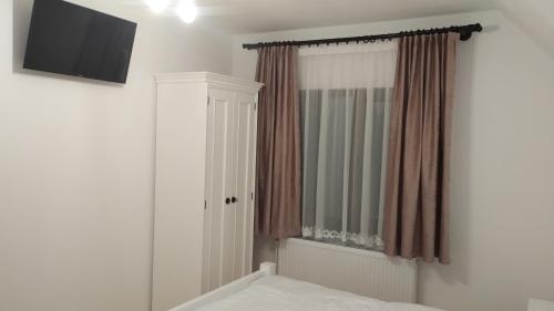 a bedroom with a bed and a television and a window at Casa Noastră in Vidra