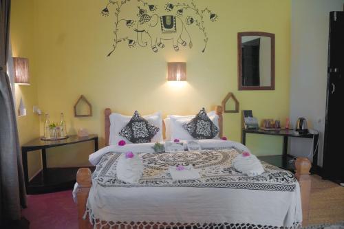 a bedroom with a large bed with white sheets and pillows at Sapana Village Lodge in Sauraha