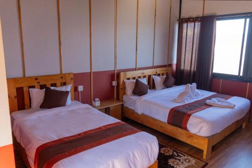 a room with two beds and a window at Suryachaur Nature Retreat in Thāpāgāon