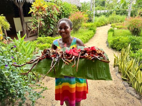 a woman in a colorful dress carrying a basket of flowers at La Parenthèse in Nosy Be