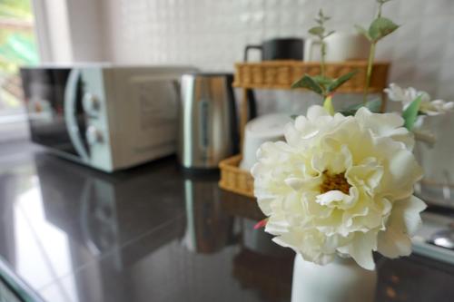 a white flower in a white vase next to a microwave at Family Friendly Home in Bangna