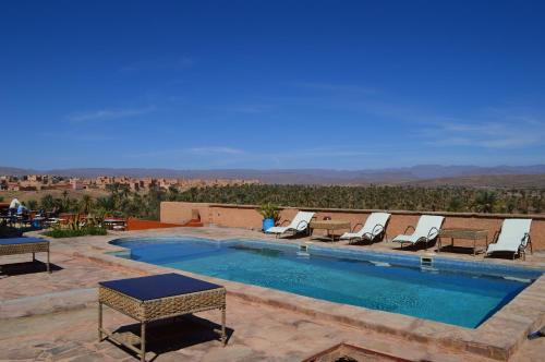 una piscina con tumbonas y vistas al desierto en Auberge Kasbah Ennakhile, en Nkob