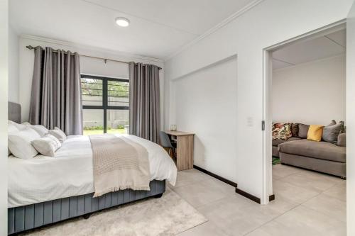 ein Schlafzimmer mit einem Bett, einer Couch und einem Spiegel in der Unterkunft Country Charm 2Bed 2Bath Fourways Sandton in Chartwell