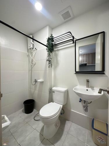a bathroom with a toilet and a sink and a mirror at Cozy Home II in Cebu City