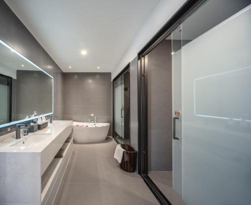 a bathroom with two sinks and a bath tub at Guanghan Exhibition International Hotel in Guanghan
