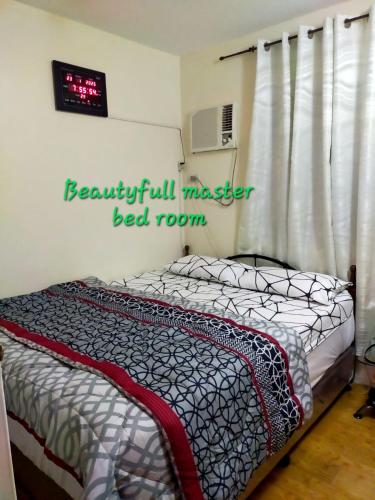 a bedroom with a bed and a clock on the wall at Two-Bedroom at San Remo Oasis in Cebu City