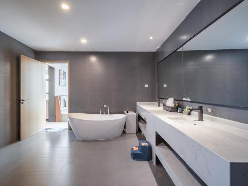 a bathroom with a large tub and two sinks at Guanghan Exhibition International Hotel in Guanghan