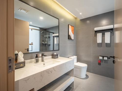 a bathroom with a sink and a mirror and a toilet at Guanghan Exhibition International Hotel in Guanghan
